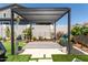 Covered pergola area featuring a decorative striped surface, seating, and garden at 19756 W Roma Ave, Litchfield Park, AZ 85340