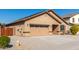 Tan house with solar panels, a two-car garage, and a fenced yard at 25360 W Fremont Ct, Buckeye, AZ 85326