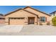 Tan house with a two-car garage and desert landscaping at 25360 W Fremont Ct, Buckeye, AZ 85326