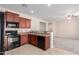 Modern kitchen with dark wood cabinets, granite countertops, and black appliances at 25360 W Fremont Ct, Buckeye, AZ 85326