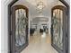 A large, ornate iron door opens into a bright foyer featuring hardwood floors and a decorative chandelier at 2916 E Arrowhead Trl, Gilbert, AZ 85297