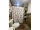 Bathroom with floral shower curtain, wood shelving, and tile flooring at 3215 W Garfield St, Phoenix, AZ 85009