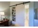 A barn door opens to reveal a bathroom and built-in shelves at 33448 N 69Th Pl, Scottsdale, AZ 85266