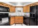 Modern kitchen with wood cabinets, black appliances, and a corner sink at 9183 W Century Dr, Arizona City, AZ 85123