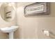 Clean and simple half-bathroom featuring a pedestal sink, a round mirror, and classic fixtures at 11163 W Edgemont Ave, Avondale, AZ 85392