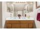 Bright bathroom featuring double sinks, wood cabinets, and a large vanity mirror at 11163 W Edgemont Ave, Avondale, AZ 85392