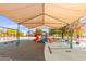 A colorful playground with slides, swings and climbing equipment, sheltered under a large shade canopy for safe play at 11163 W Edgemont Ave, Avondale, AZ 85392
