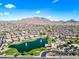Aerial view of a community with a pond, clubhouse, and pool surrounded by lush green landscaping and mountain views at 2776 E Mews Rd, Gilbert, AZ 85298