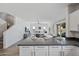 Open-concept kitchen with granite countertops, white cabinetry, and an eat-in island overlooking the spacious living area at 2776 E Mews Rd, Gilbert, AZ 85298