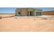 A light green home with a stone accent wall in a desert setting, awaiting landscaping at 28583 N 257Th Dr, Wittmann, AZ 85361