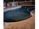 Kidney-shaped pool at night with surrounding patio and lighting at 12450 W Fieldstone Dr, Sun City West, AZ 85375