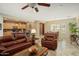 Spacious living room with leather sofas, coffee table, and ceiling fan at 23313 N De La Guerra Ct, Sun City West, AZ 85375