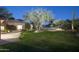 Evening backyard featuring lush green lawn, desert landscaping, mature trees, and a gated pool at 3439 E Tonto Dr, Phoenix, AZ 85044