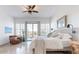 Bright main bedroom featuring white bedding, shutters, a ceiling fan, and an outdoor patio at 42225 N Celebration Way, Phoenix, AZ 85086