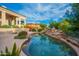 Inviting pool with a natural rock waterfall feature, mature landscaping, and blue skies overhead creating a serene outdoor oasis at 15701 E Greystone Dr, Fountain Hills, AZ 85268