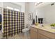 Bright bathroom with a large mirror, neutral tile flooring, and a blue and yellow plaid shower curtain at 23114 N 146Th Dr, Sun City West, AZ 85375