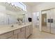 Bright bathroom featuring dual sinks, vanity lighting, a tile floor, and a sliding glass shower enclosure at 23114 N 146Th Dr, Sun City West, AZ 85375