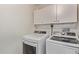 Bright laundry room with washer, dryer, and overhead cabinets at 2650 W Union Hills Dr # 108, Phoenix, AZ 85027