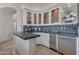 Elegant wet bar features glass-front cabinetry, granite countertops, and a mini-fridge at 29600 N 106Th N Pl, Scottsdale, AZ 85262