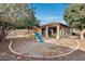 Backyard with covered patio, playground, and mature trees at 29762 N 69Th Ln, Peoria, AZ 85383