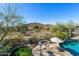 A luxurious backyard features a pool, a fire pit, an outdoor kitchen, and desert landscaping at 3652 N Sonoran Hts, Mesa, AZ 85207