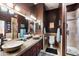 Stylish bathroom with dual vessel sinks, rich wood cabinetry, and a walk-in shower with travertine surround at 3652 N Sonoran Hts, Mesa, AZ 85207