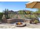 Enjoy evenings outside next to the circular fire pit with built-in seating and desert views beyond the fence at 3652 N Sonoran Hts, Mesa, AZ 85207