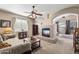 Spacious living room featuring a fireplace, ceiling fan, and arched doorways with a cozy sofa and carpeted floors at 3652 N Sonoran Hts, Mesa, AZ 85207