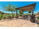 Community patio with pergola, tables, chairs, and views of a lake at 42621 W Heavenly Pl, Maricopa, AZ 85138