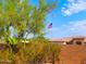 View of an American Flag waving in the breeze in front of Southwestern architecture against a clear blue sky at 44311 N 1St Dr, New River, AZ 85087