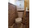 Compact toilet featuring white fixture, storage cabinet, and faux brick wall at 44311 N 1St Dr, New River, AZ 85087