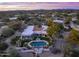 A twilight aerial view of a sprawling estate with a pool, lush landscaping, and desert surroundings at 8119 E Foothills Dr, Scottsdale, AZ 85255