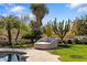 Lush backyard with a modern chaise lounge, unique cacti, palm trees and vibrant greenery near the pool at 8119 E Foothills Dr, Scottsdale, AZ 85255