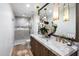 Bathroom featuring dual sinks with marble countertops, wood cabinets, a glass shower, and gold fixtures at 8119 E Foothills Dr, Scottsdale, AZ 85255