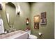 Charming powder room with unique stone sink, custom mirror and fixtures, and olive-green walls at 8119 E Foothills Dr, Scottsdale, AZ 85255