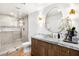 Modern bathroom with glass shower, unique mirror, wood cabinets with marble countertop and gold fixtures at 8119 E Foothills Dr, Scottsdale, AZ 85255