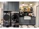 Stylish laundry room with black cabinets, marble countertops, modern appliances, and checkered floors at 8119 E Foothills Dr, Scottsdale, AZ 85255