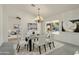 Dining area showcasing a glass table, white chairs, chandelier, and view of the backyard patio and fireplace at 15406 W Pinchot Ct, Goodyear, AZ 85395