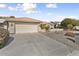 A charming home featuring a two-car garage, desert landscaping, and mature trees at 15406 W Pinchot Ct, Goodyear, AZ 85395