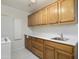 Well-lit laundry room with wood cabinets, white countertop, and tile floor at 15406 W Pinchot Ct, Goodyear, AZ 85395