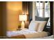 Cozy bedroom featuring a bed with a plush comforter, a lamp, and a window with curtains at 305 W Lewis Ave, Phoenix, AZ 85003