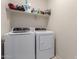 Efficient laundry room with modern white washer and dryer and ample shelving for storage at 41917 W Manderas Ln, Maricopa, AZ 85138