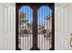 View through security doors to covered patio with outdoor seating and charming desert landscape beyond at 7307 E Texas Ebony Dr, Gold Canyon, AZ 85118