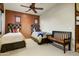 Neutral toned bedroom with a ceiling fan, decorative bench and rust accent wall at 8260 E Sunset View Dr, Gold Canyon, AZ 85118
