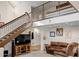 Living room with a brown leather couch, a large TV, and a staircase at 1112 W Citation Dr, Chandler, AZ 85224