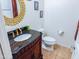 Bathroom with dark vanity, toilet and decorative mirror at 16846 W Hilton Ave, Goodyear, AZ 85338