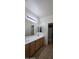 Bathroom vanity with double sinks, wooden cabinets, large mirror and decorative lighting fixtures above at 16846 W Hilton Ave, Goodyear, AZ 85338