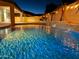 Relaxing nighttime view of a sparkling pool and waterfall feature at 16846 W Hilton Ave, Goodyear, AZ 85338