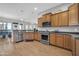 Stylish kitchen with stainless steel appliances, wood cabinets, and open to dining area at 22717 W Sierra Ridge Way, Wittmann, AZ 85361