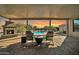 Covered patio featuring a cozy seating area with a fireplace, overlooking a sparkling pool and lush landscaping at 22717 W Sierra Ridge Way, Wittmann, AZ 85361